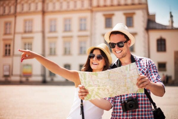 A man and woman holding a map in front of a building.