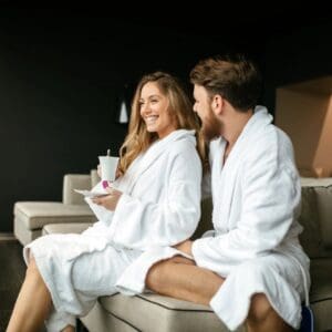 A man and woman in white robes sitting on a couch.