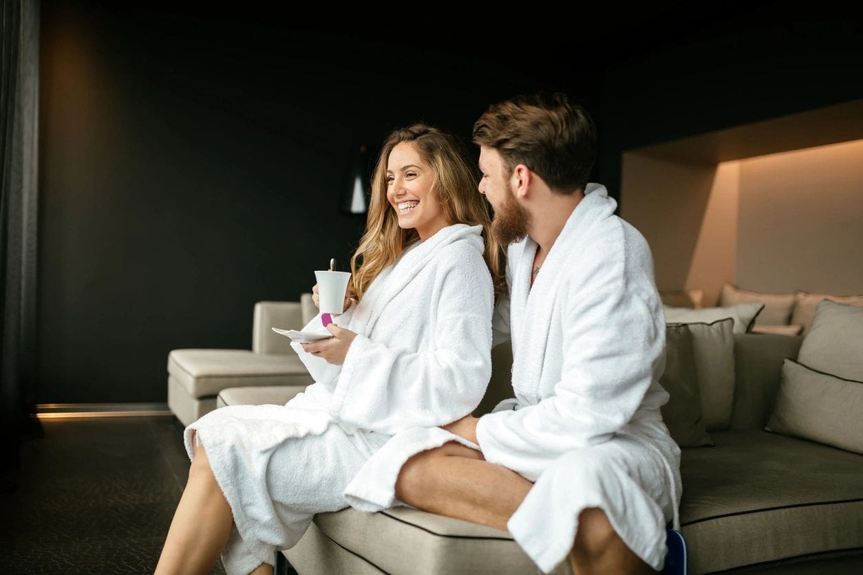 A man and woman in white robes sitting on a couch.